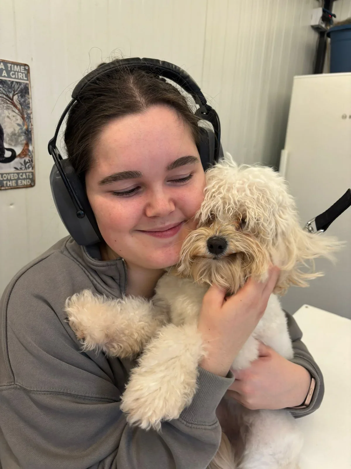 Femke houdt een kleine hond vast in de trimsalon.